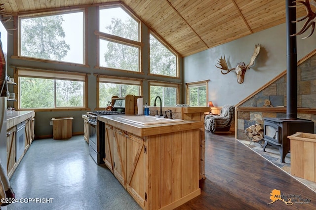 kitchen featuring wood ceiling, a wood stove, a sink, gas range, and high vaulted ceiling