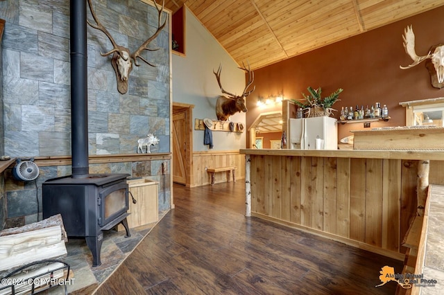 bar featuring a wood stove, dark hardwood / wood-style floors, white refrigerator with ice dispenser, wood walls, and vaulted ceiling