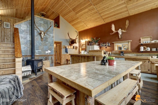 kitchen with wood ceiling, high vaulted ceiling, dark wood-type flooring, and a wood stove