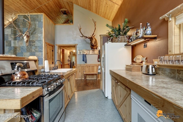 kitchen featuring stainless steel gas range oven, wooden ceiling, freestanding refrigerator, high vaulted ceiling, and a sink