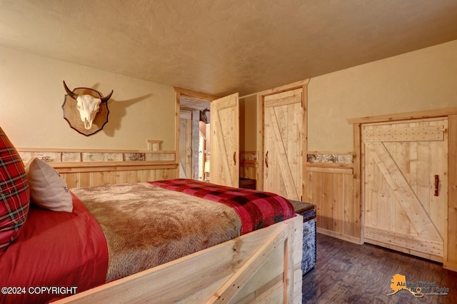 bedroom with a wainscoted wall, wood walls, and wood finished floors