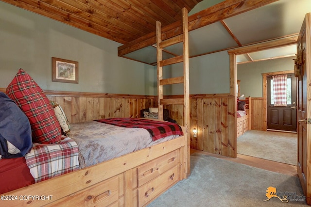 carpeted bedroom featuring lofted ceiling and wooden walls