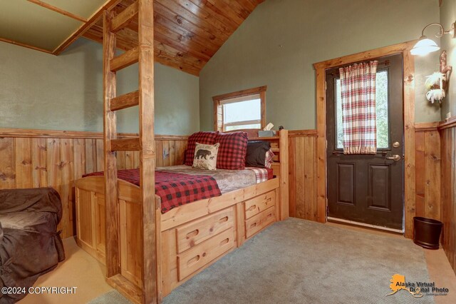 bedroom featuring vaulted ceiling, carpet floors, wood walls, and wainscoting