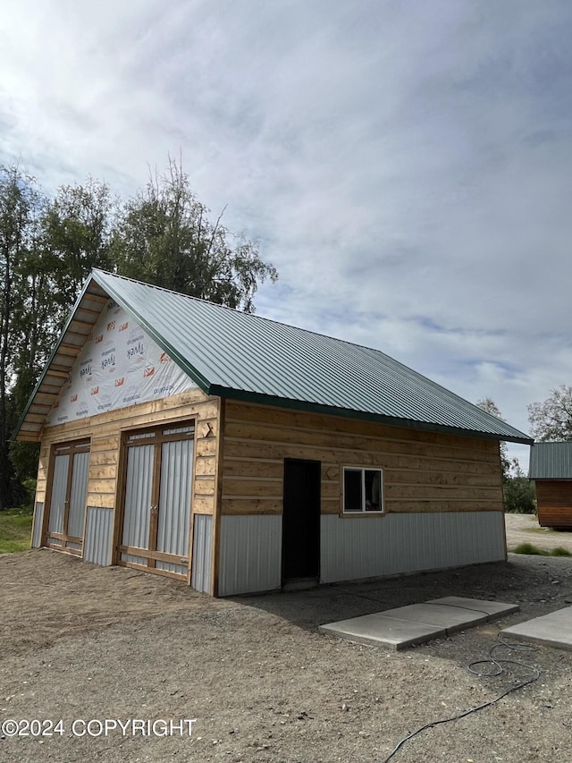 view of property exterior with metal roof and a detached garage