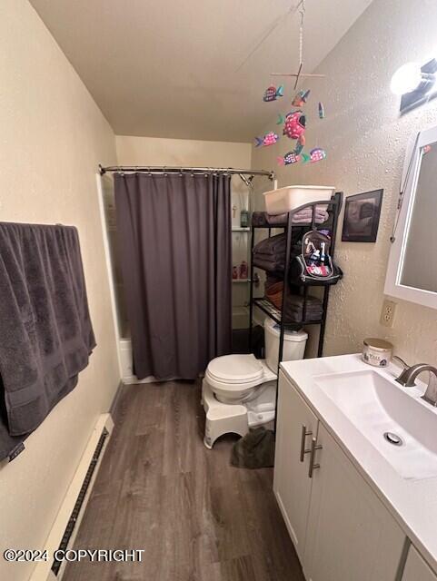 bathroom featuring lofted ceiling, toilet, a baseboard radiator, vanity, and hardwood / wood-style floors