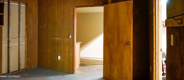 unfurnished bedroom featuring wooden walls and concrete floors