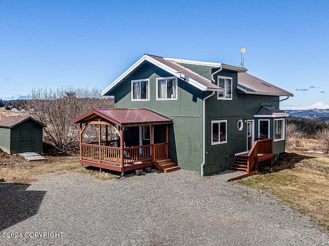 back of house with a storage shed