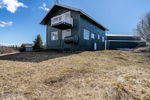 back of house featuring a balcony and a lawn