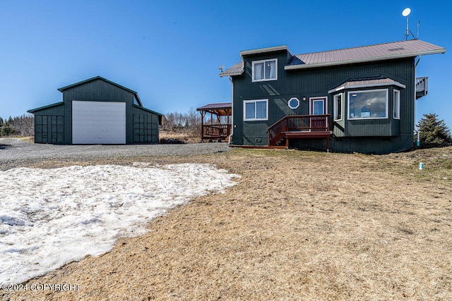 rear view of property featuring an outdoor structure, a deck, and a garage