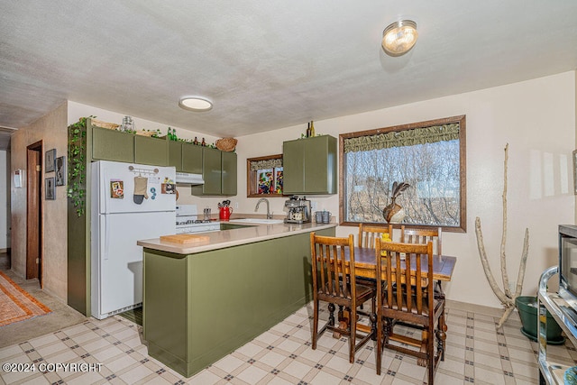 kitchen with green cabinets, white appliances, kitchen peninsula, sink, and light tile floors