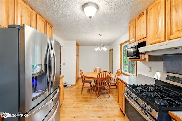 44775 Carver Dr, Kenai, AK 99611 - kitchen with stainless steel appliances, under cabinet range hood, light wood-style floors, a chandelier, and a textured ceiling