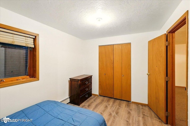 44775 Carver Dr, Kenai, AK 99611 - bedroom with light wood-style flooring, a closet, a textured ceiling, and a baseboard heating unit