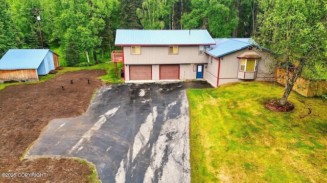 44775 Carver Dr, Kenai, AK 99611 - view of front of home with driveway, metal roof, a garage, a front yard, and a view of trees