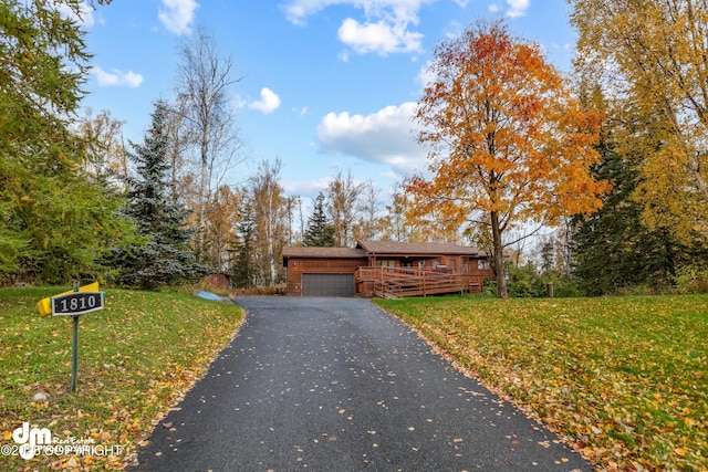 view of front of home with aphalt driveway, a front lawn, and an attached garage