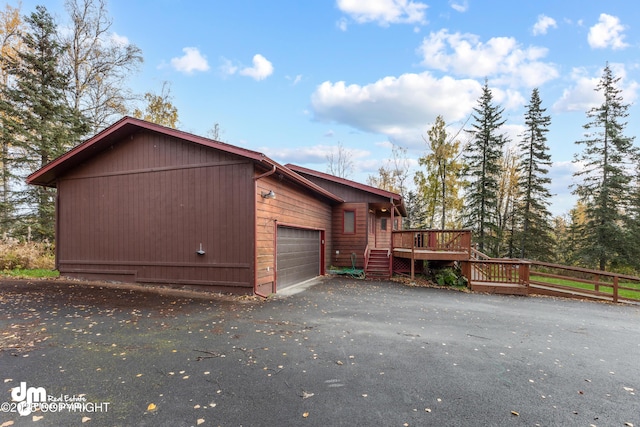 view of side of home with aphalt driveway and a deck