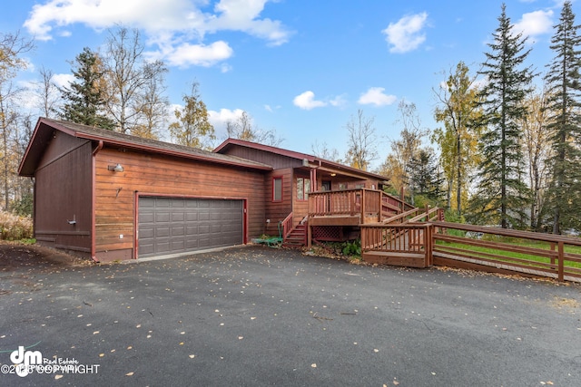 rustic home with a garage, driveway, and stairs