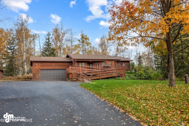 chalet / cabin with a garage, driveway, a deck, and a front yard