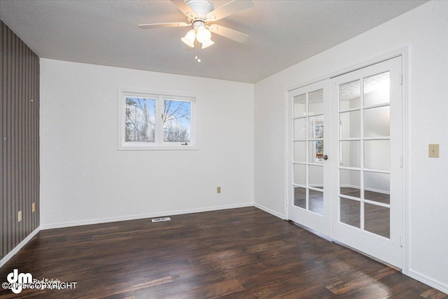 empty room with ceiling fan, a textured ceiling, dark wood-type flooring, baseboards, and french doors