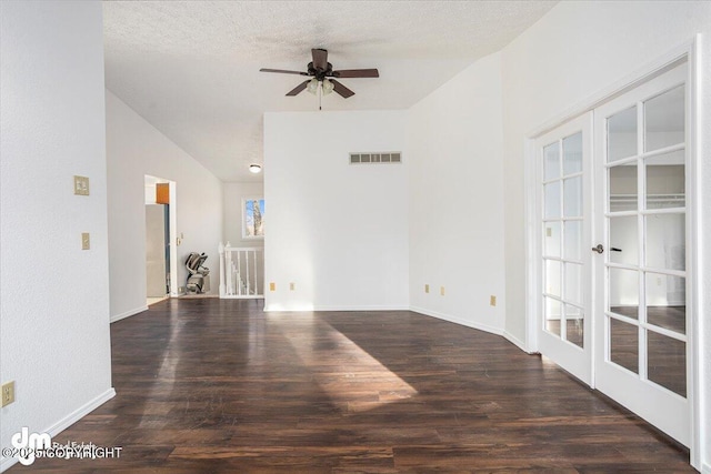 empty room featuring visible vents, lofted ceiling, dark wood-style flooring, a textured ceiling, and french doors