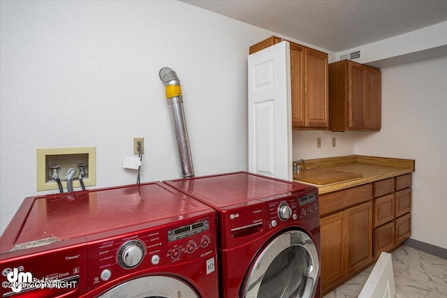 laundry area featuring marble finish floor, washing machine and clothes dryer, cabinet space, a sink, and a textured ceiling