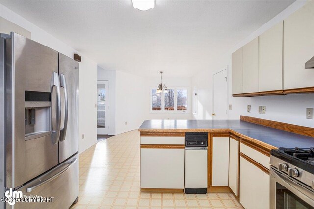 kitchen with appliances with stainless steel finishes, a peninsula, light floors, white cabinetry, and pendant lighting