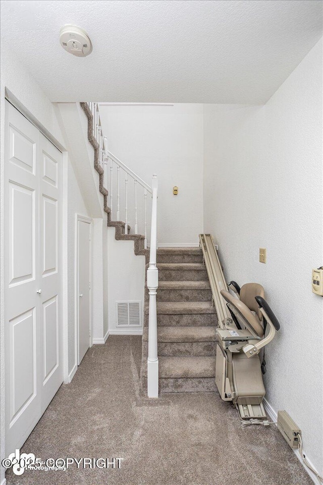 stairway with baseboards, a textured ceiling, visible vents, and carpet flooring