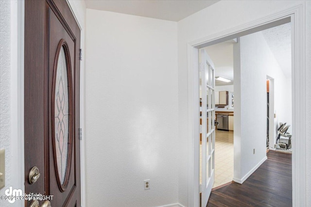 corridor featuring dark wood-type flooring and baseboards