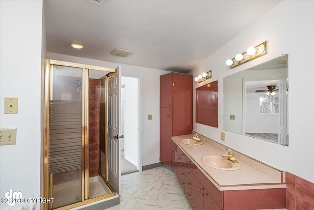 full bathroom with marble finish floor, a textured ceiling, a sink, and a stall shower