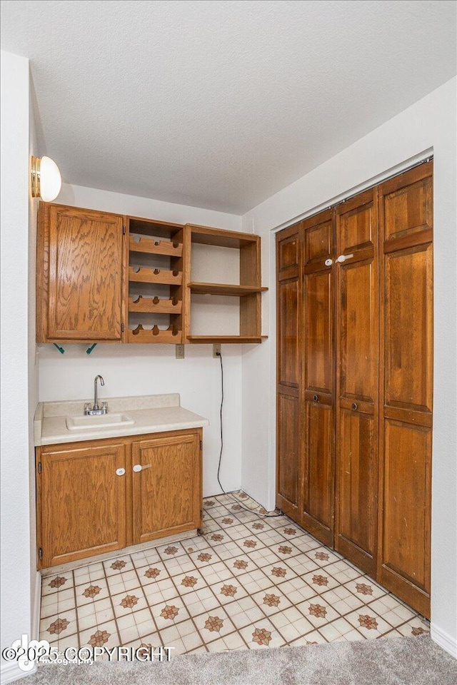 kitchen with light countertops, open shelves, a sink, and brown cabinets