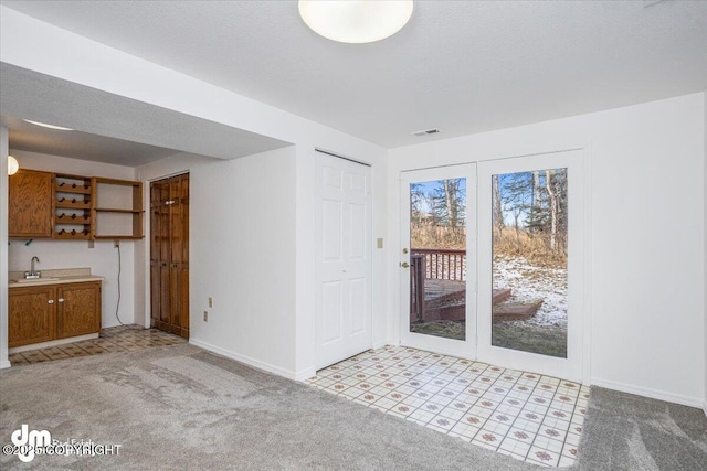 interior space with baseboards, a textured ceiling, indoor wet bar, and light colored carpet