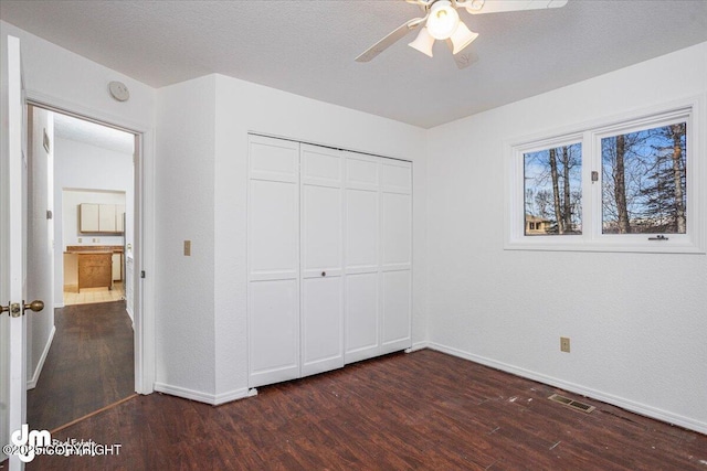 unfurnished bedroom featuring a closet, dark wood finished floors, visible vents, and baseboards