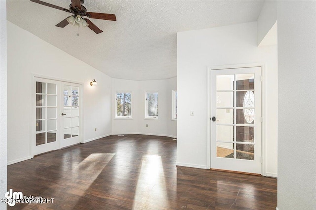 unfurnished room featuring lofted ceiling, dark wood-style flooring, a textured ceiling, and french doors