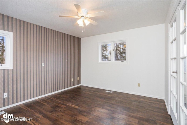 unfurnished bedroom featuring visible vents, dark wood-type flooring, a textured ceiling, baseboards, and wallpapered walls