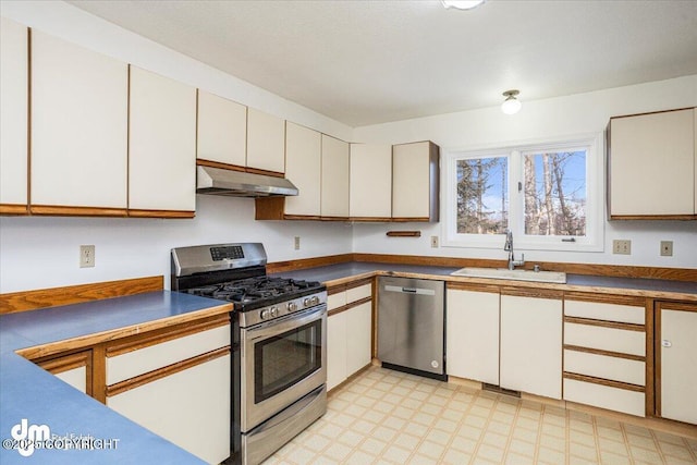 kitchen with appliances with stainless steel finishes, white cabinetry, a sink, and under cabinet range hood