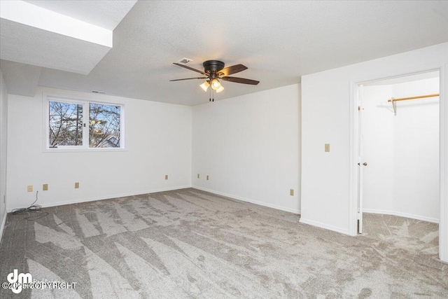 unfurnished bedroom featuring visible vents, a walk in closet, light carpet, and a textured ceiling