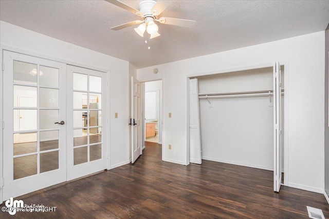 unfurnished bedroom featuring a textured ceiling, visible vents, french doors, a closet, and dark wood-style floors