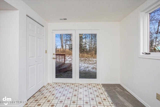 doorway with visible vents, a wealth of natural light, and baseboards