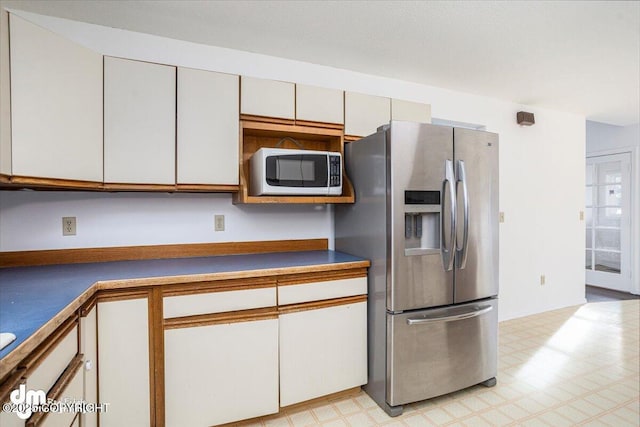 kitchen featuring white cabinets, stainless steel fridge, and light floors