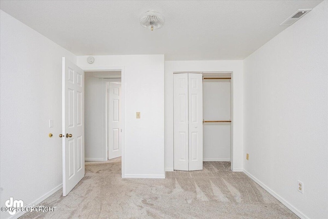 unfurnished bedroom with light carpet, a closet, visible vents, and baseboards