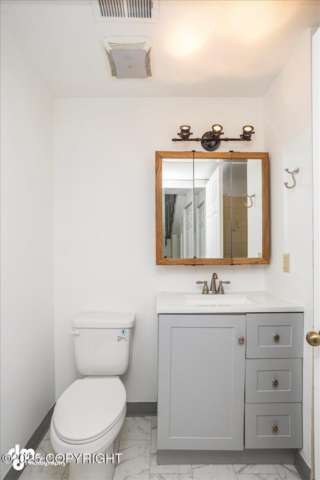 bathroom featuring toilet, vanity, visible vents, baseboards, and marble finish floor