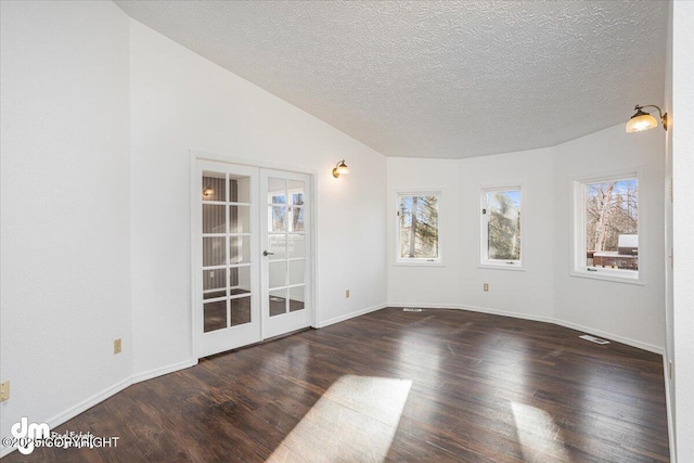 empty room with french doors, dark wood finished floors, visible vents, vaulted ceiling, and a textured ceiling