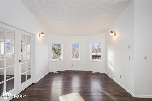 spare room featuring dark wood-style floors, french doors, a textured ceiling, and baseboards