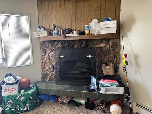 interior details with a stone fireplace, carpet floors, wooden walls, and a baseboard heating unit