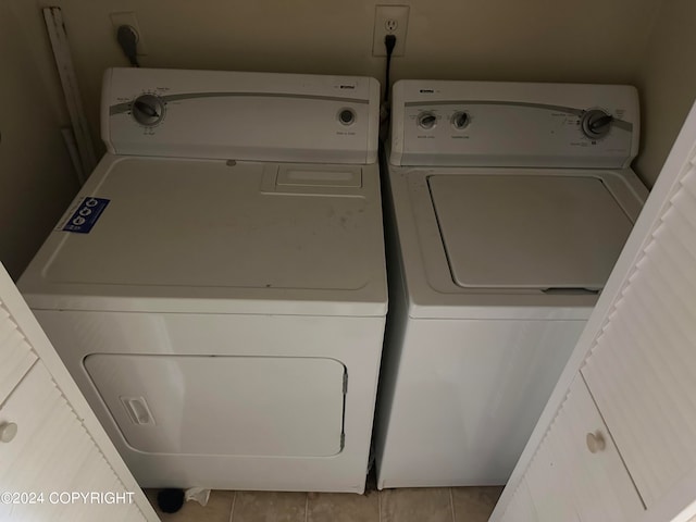 laundry area with hookup for an electric dryer, light tile floors, and washing machine and clothes dryer