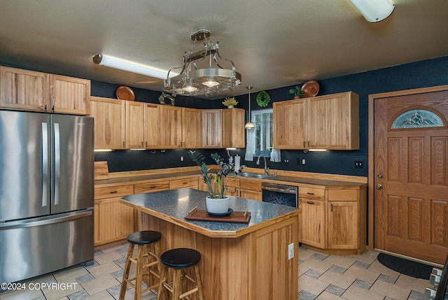 kitchen with a kitchen island, a breakfast bar, sink, dishwashing machine, and stainless steel fridge