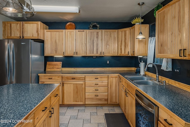 kitchen with stainless steel appliances, sink, light brown cabinetry, and decorative light fixtures