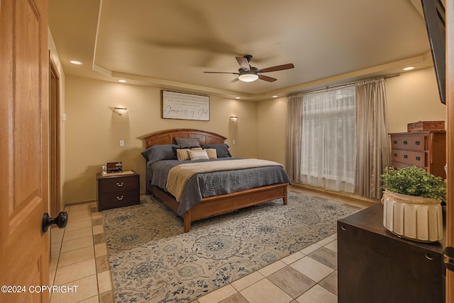 bedroom featuring a raised ceiling, light tile patterned floors, and ceiling fan