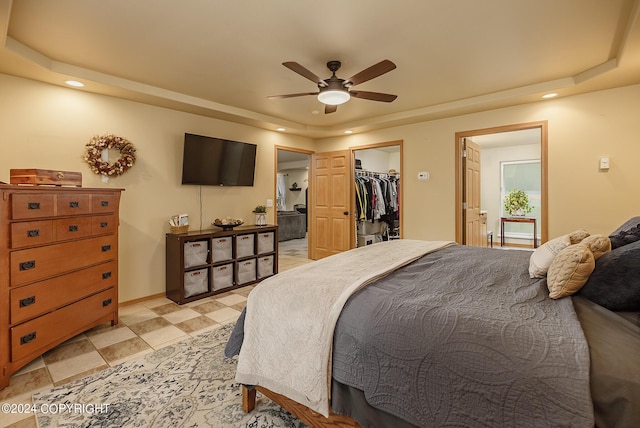 bedroom featuring ceiling fan, a spacious closet, a raised ceiling, and a closet