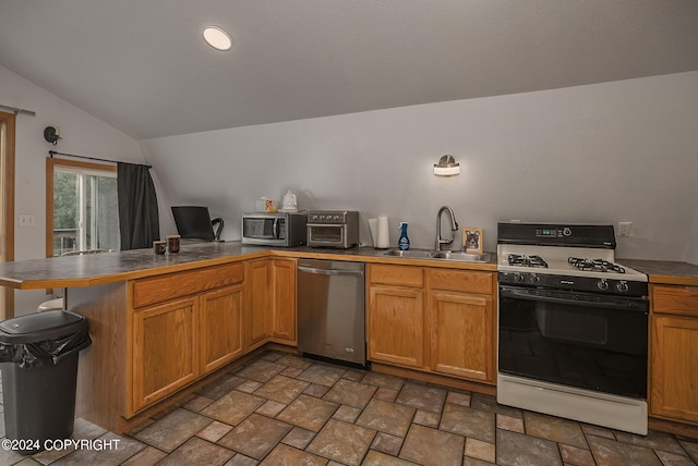 kitchen with lofted ceiling, sink, appliances with stainless steel finishes, a kitchen breakfast bar, and kitchen peninsula