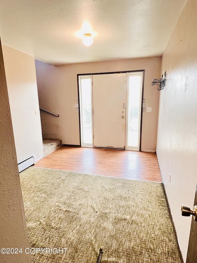 entryway featuring wood-type flooring, a baseboard heating unit, and a textured ceiling